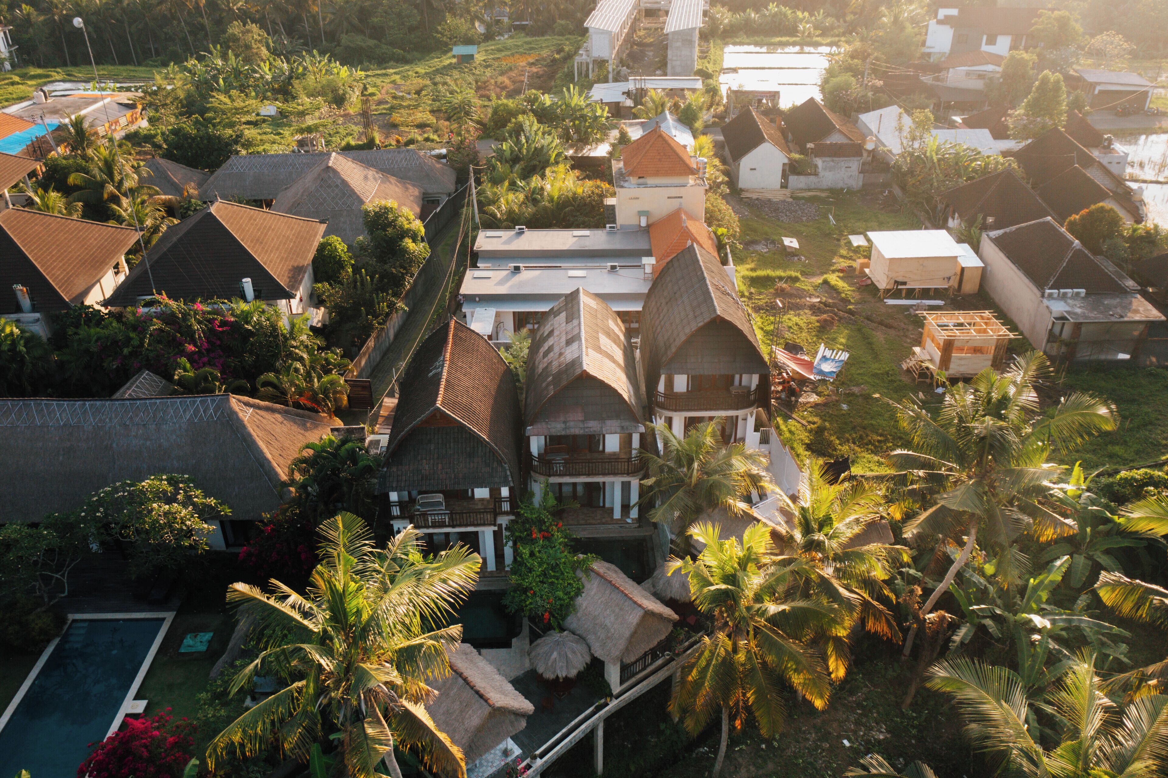 Vue aérienne d’un complexe hôtelier comprenant plusieurs bâtiments de style bungalow, une piscine et une végétation tropicale luxuriante.