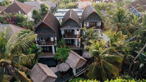 A resort with thatched-roof bungalows, a swimming pool, and lush tropical vegetation. - Ganesha Villa (Ubud)
