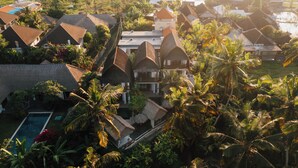 A resort with thatched-roof villas, a swimming pool, and lush tropical vegetation. - Ganesha Villa (Ubud)