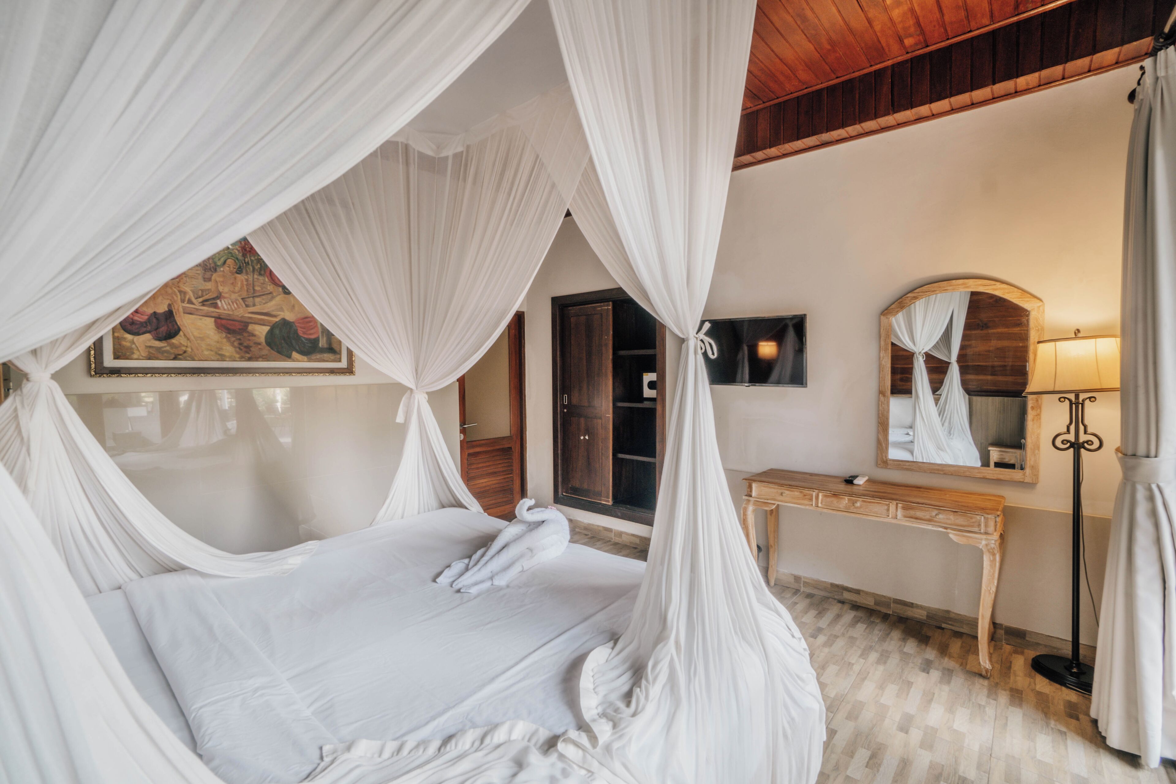 A bedroom with a canopy bed, a wooden dresser, a mirror, and a painting on the wall.