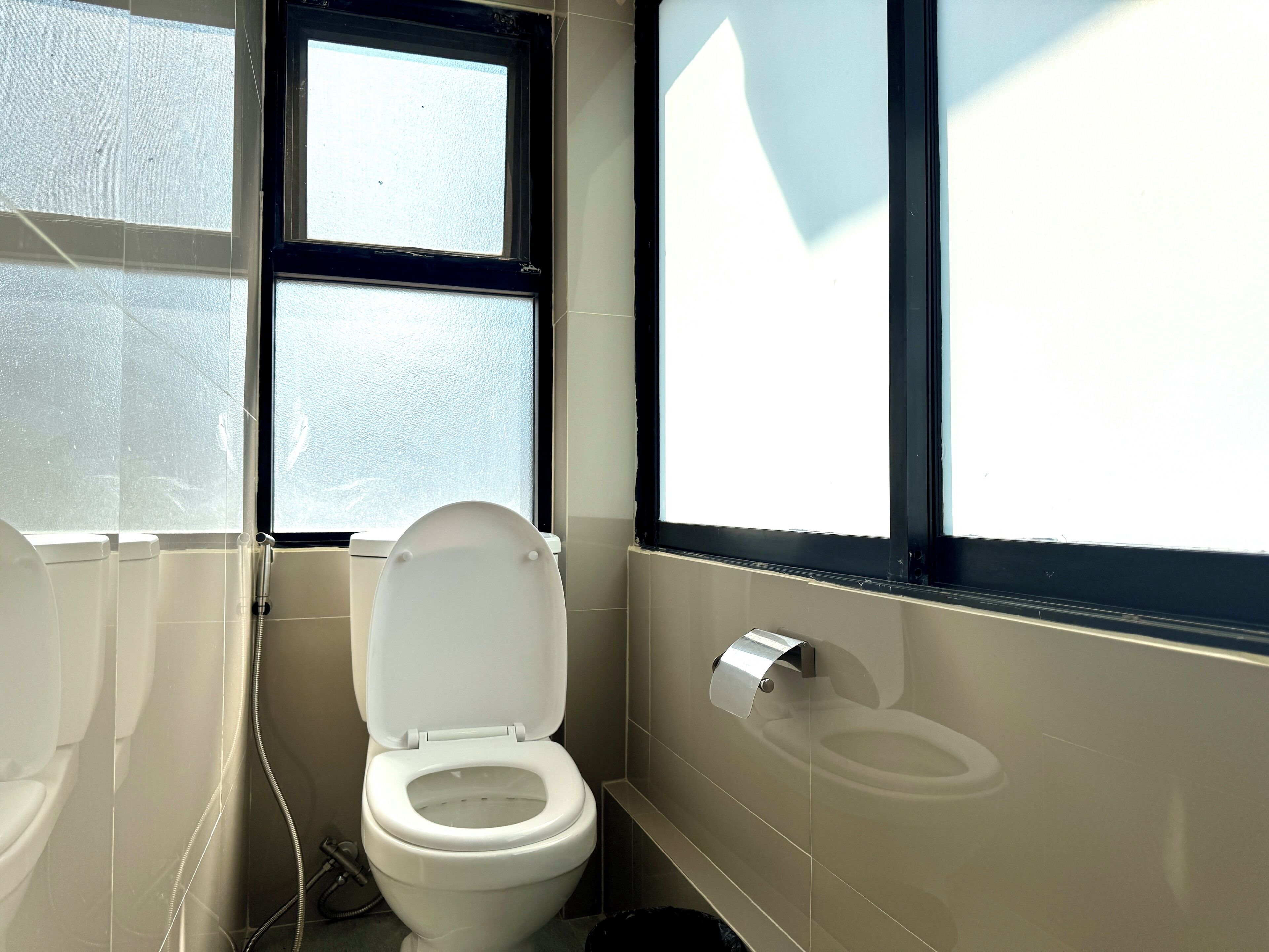 A bathroom with a toilet, a bidet, and a window.