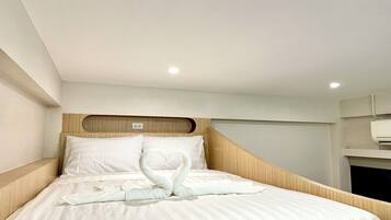 Une chambre d’hôtel avec un lit bien fait, une tête de lit en bois et un climatiseur fixé au mur.