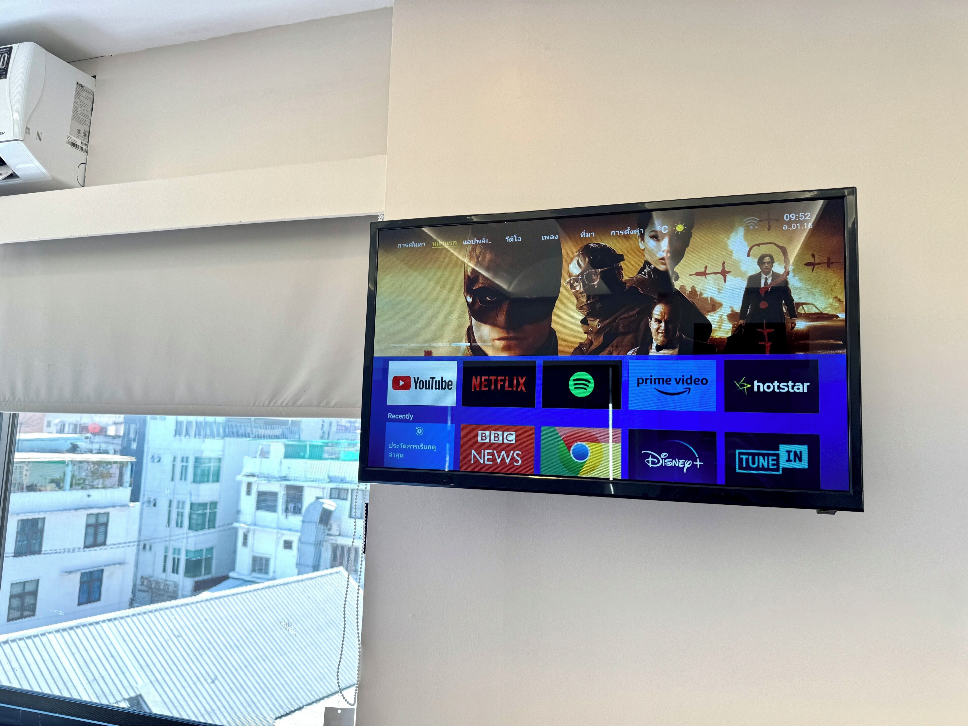 A flat-screen TV mounted on a wall displaying various streaming services and a YouTube channel.