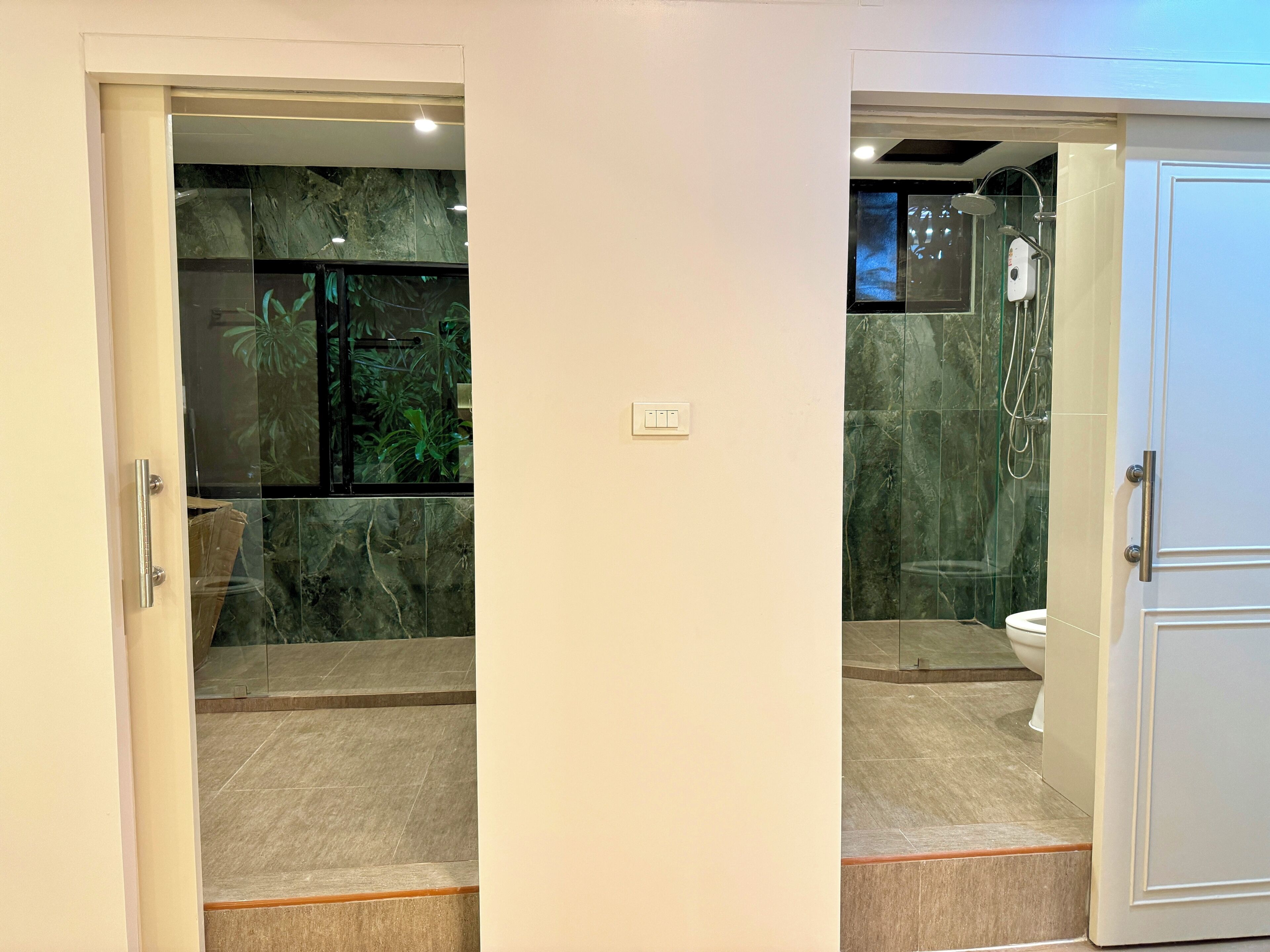 A bathroom with a glass shower enclosure, a toilet, and a sink.