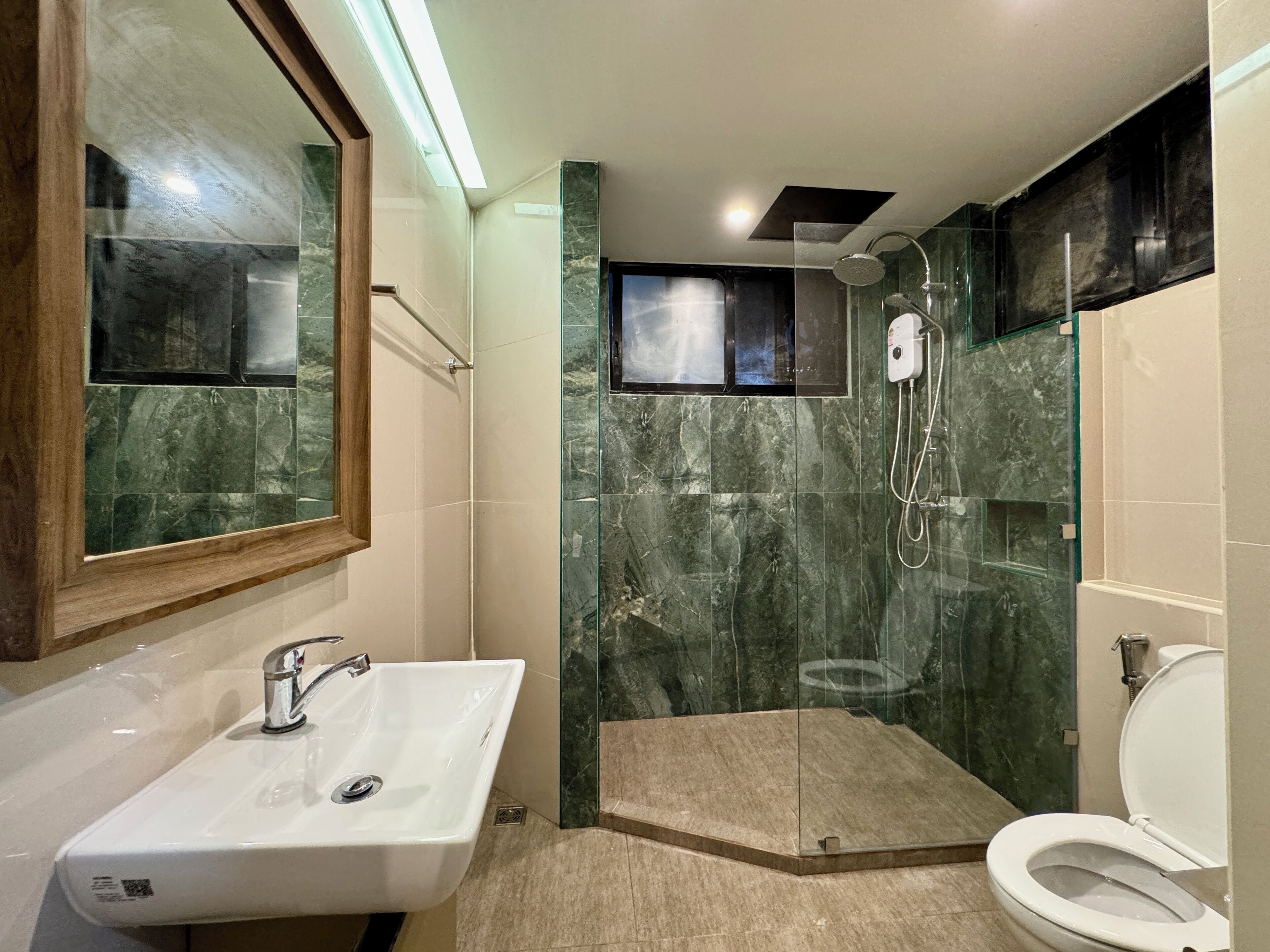 Une salle de bain équipée d’un lavabo, d’un miroir, d’une douche et de toilettes.