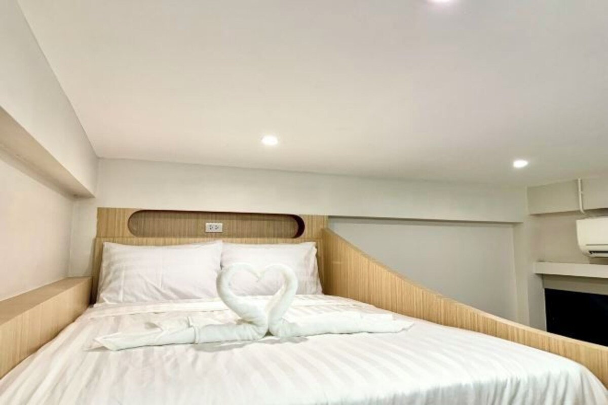 A neatly made bed with a swan-shaped towel arrangement.