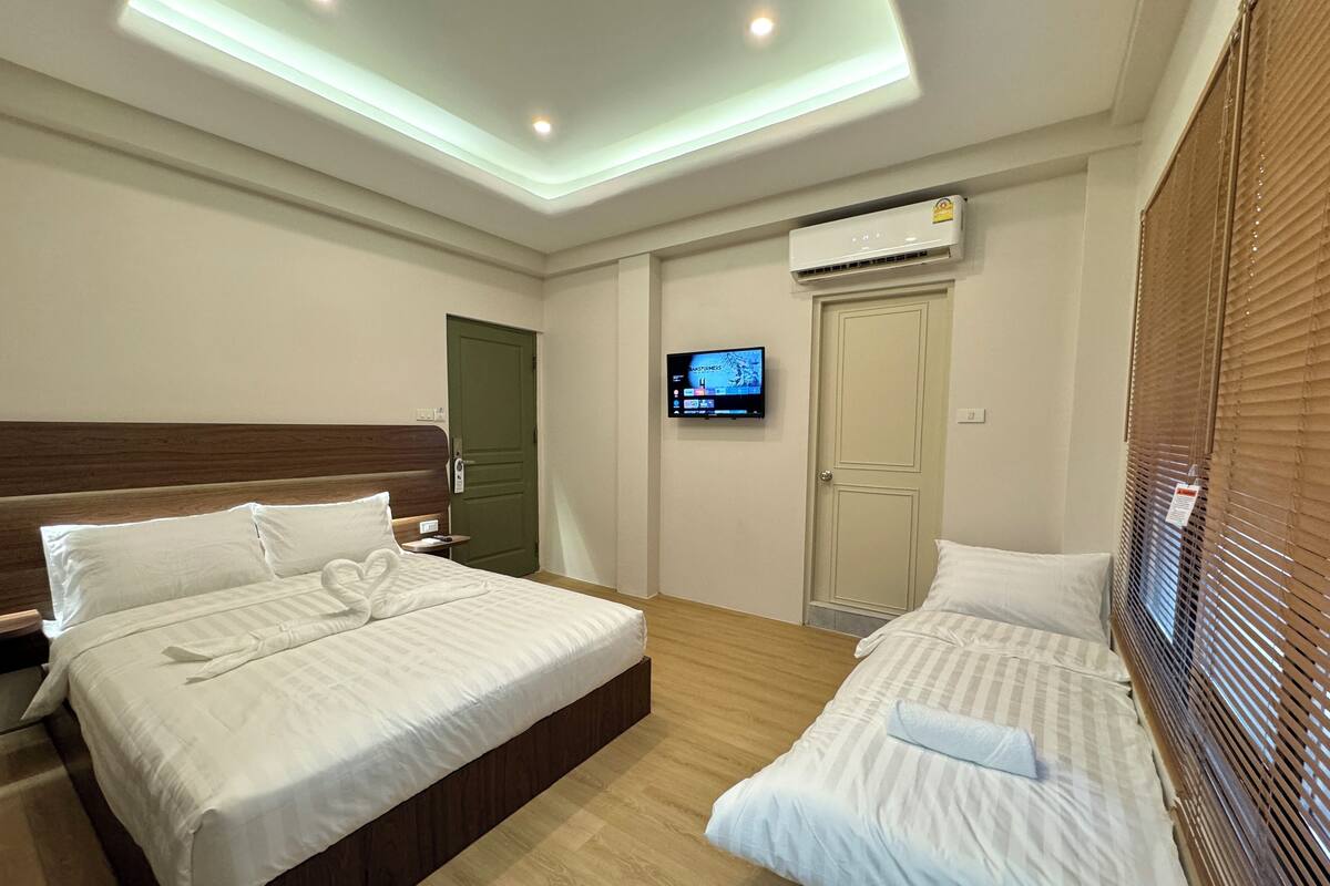 Ein Hotelzimmer mit zwei Betten, einem Fernseher, einer Klimaanlage und einer Deckenleuchte.