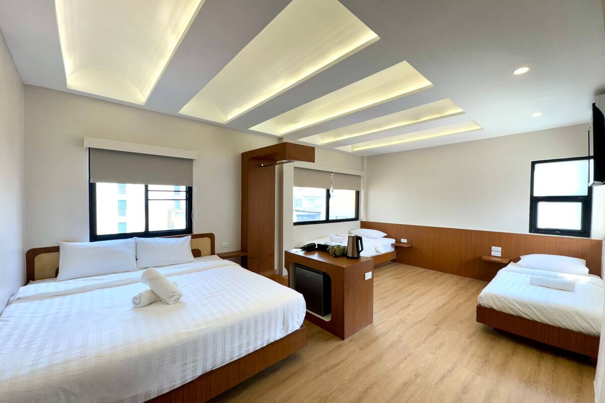 Ein Hotelzimmer mit zwei Betten, einem Schreibtisch, einem Sessel und einem Fernseher.