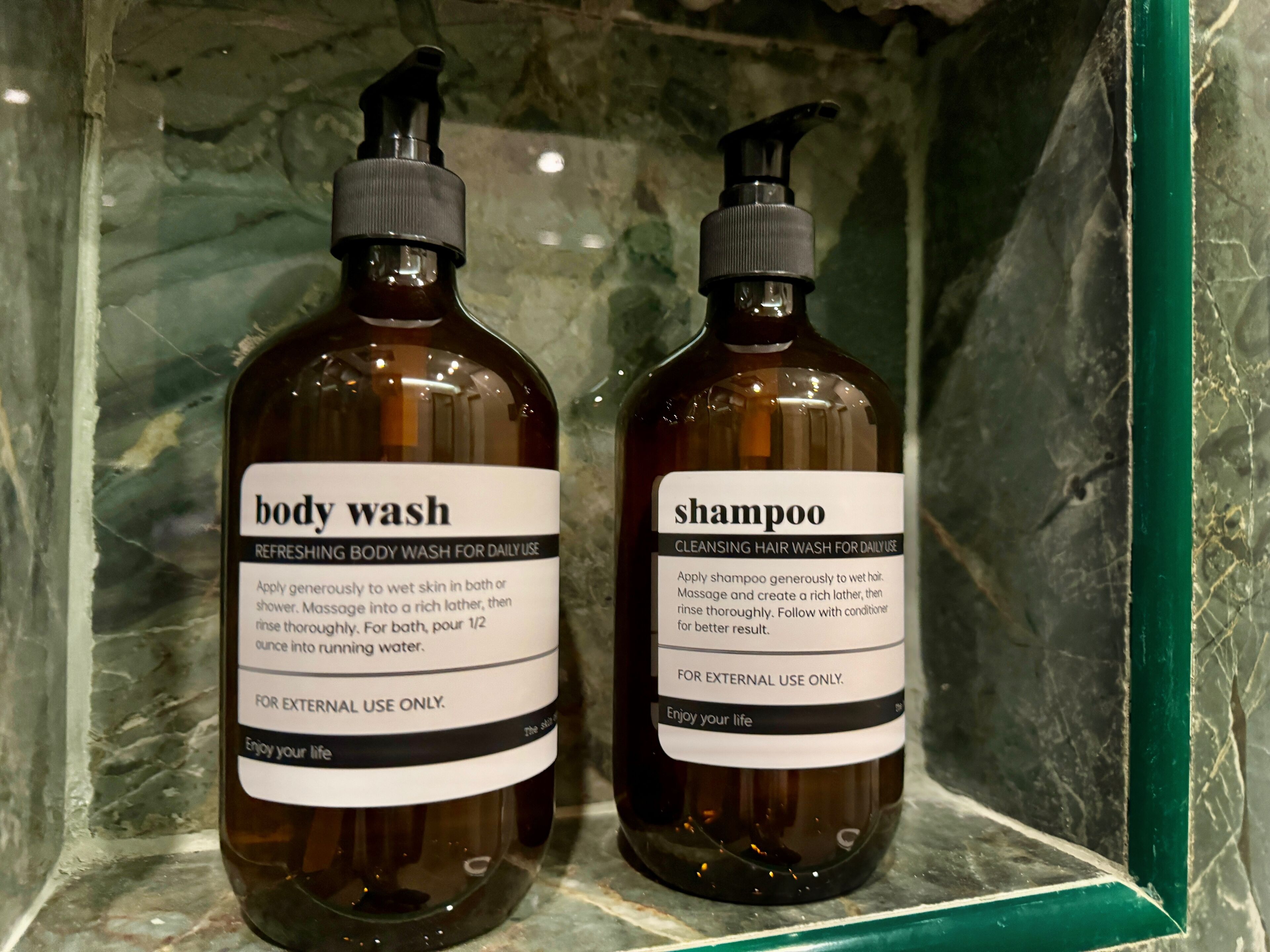 Zwei Flaschen Duschgel und Shampoo in einem Badezimmer.