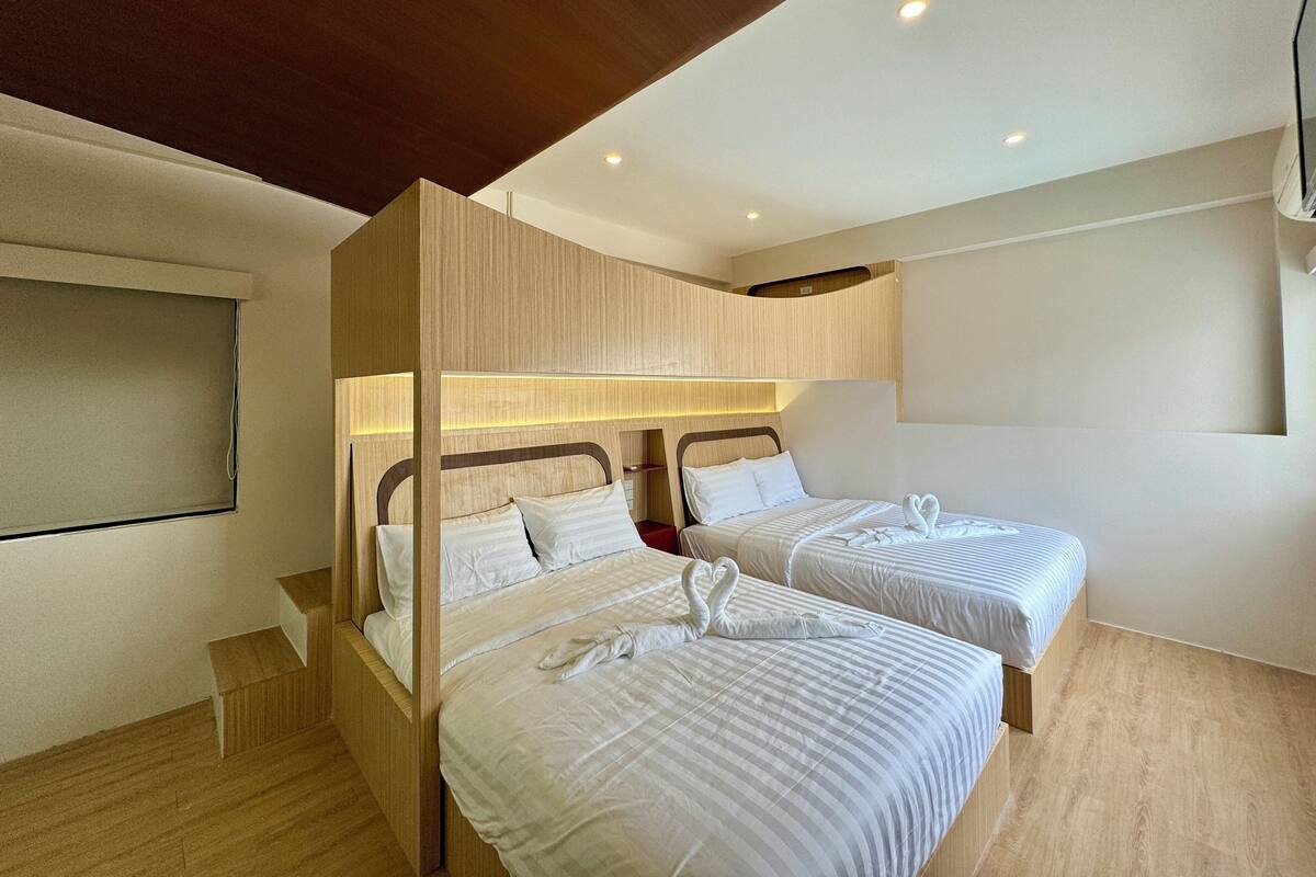 Ein Hotelzimmer mit zwei Betten, Holz-Kopfteilen und einer Decke mit eingelassenen Leuchten.