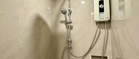 A shower with a handheld showerhead, a wall-mounted control panel, and a bottle of shampoo.
