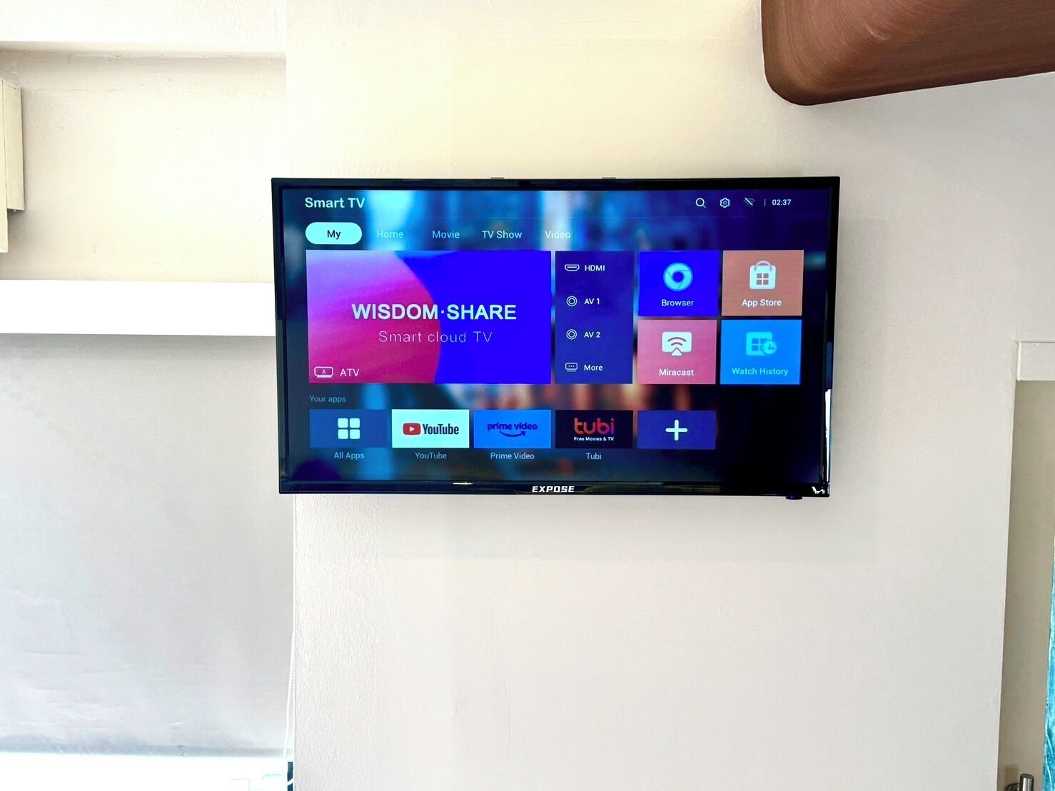 Televisor de pantalla plana montado en la pared que muestra una interfaz inteligente con diversas aplicaciones de transmisión.
