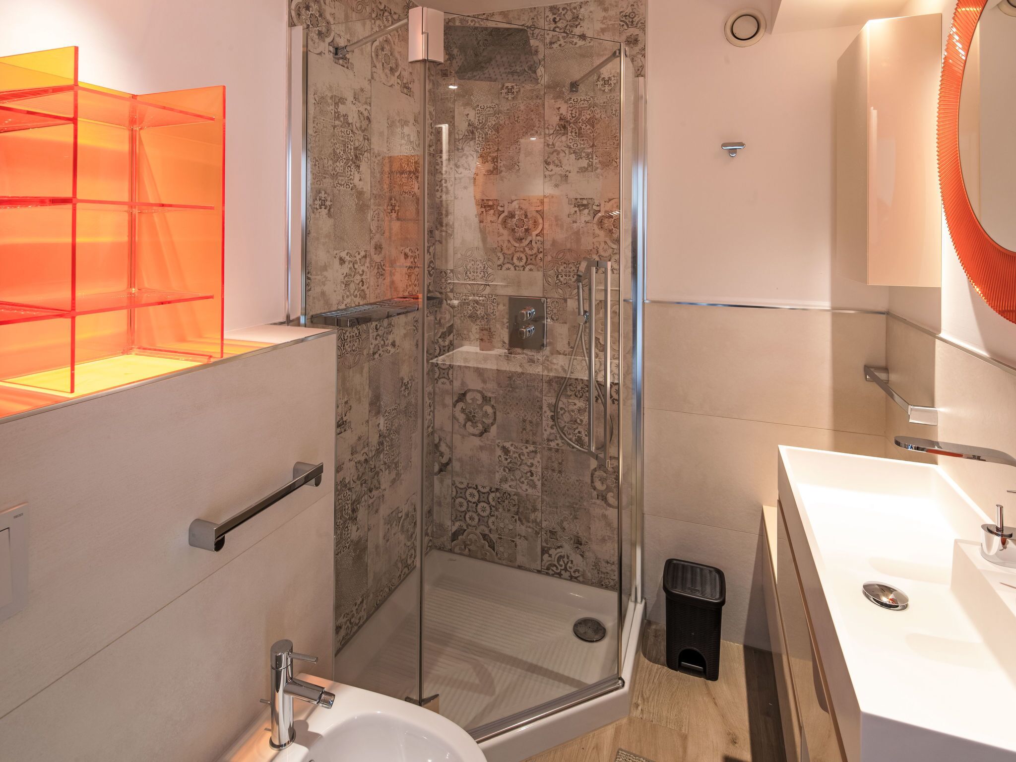 Een moderne badkamer met een douchecabine van glas, een wit wastafelmeubel en een glazen schapunit.