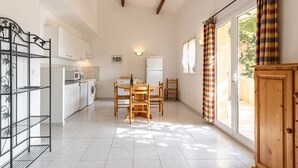 Una cocina amplia con armarios blancos, una mesa de comedor con sillas y vistas a través de un ventanal.