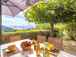An outdoor dining table with a view of the sea, surrounded by greenery and a tree. - Murticcio 2 by Interhome (Bonifacio)