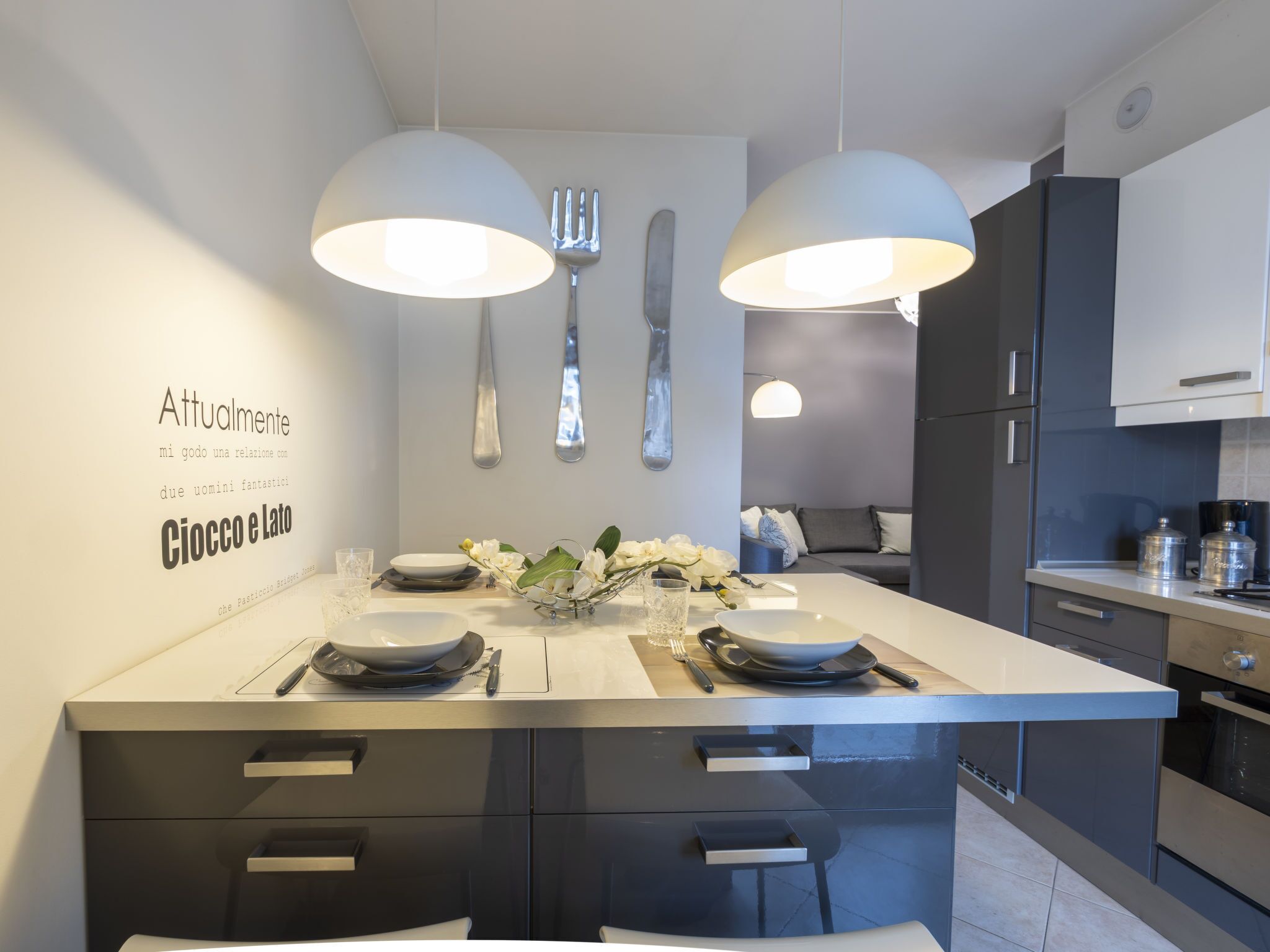 A modern kitchen with a central island, dark cabinetry, and pendant lighting.