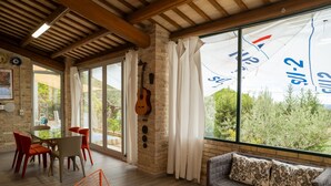 Ein geräumiger Wohnbereich mit großem Fenster, einer Gitarre an der Wand und einer gemütlichen Sitzecke.