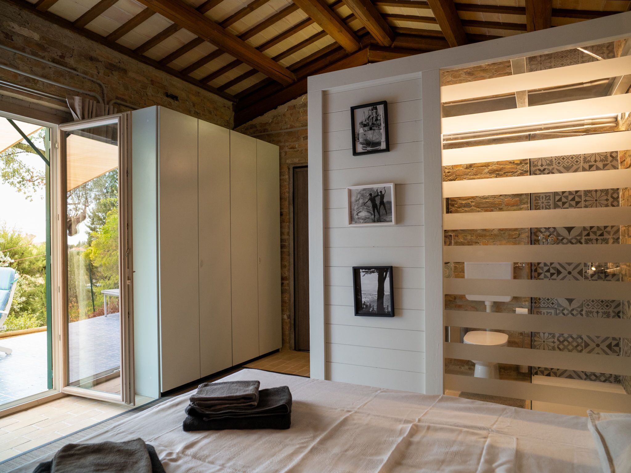 A bedroom with a bed, a wardrobe, and a wall with framed pictures.