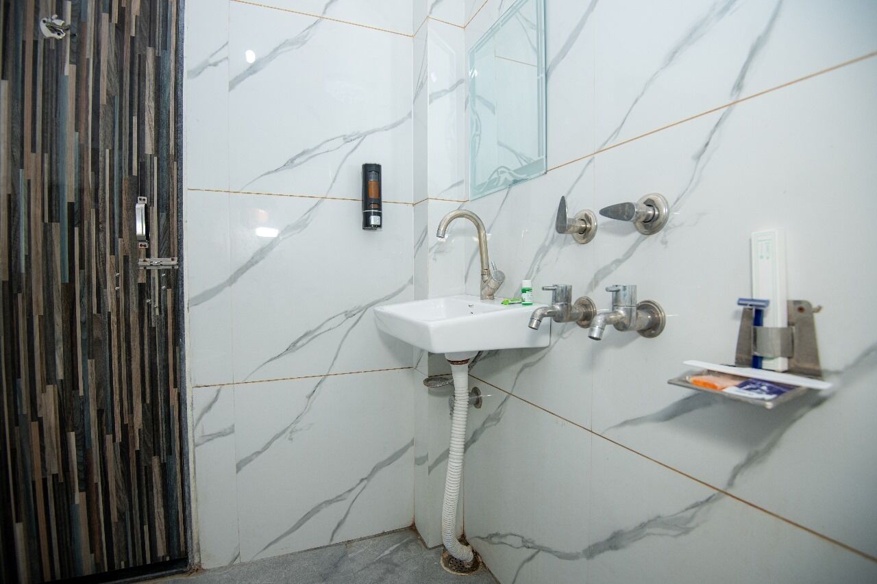 A bathroom with a white marble sink, a glass shower enclosure, and a wooden door.