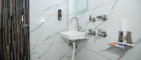 A bathroom with a white marble sink, a glass shower enclosure, and a wooden door.
