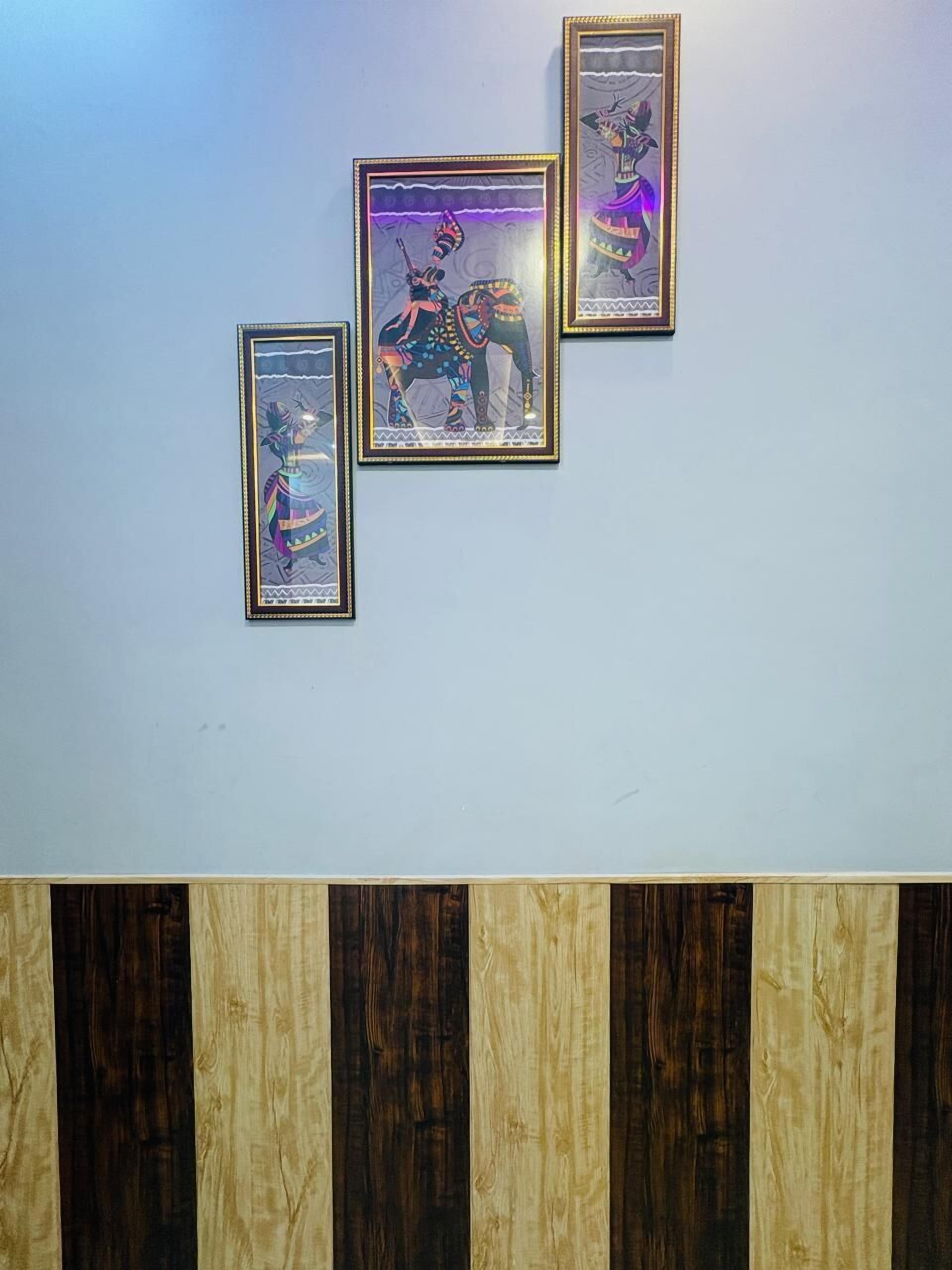 Três obras de arte emolduradas numa parede, com um painel de madeira abaixo.