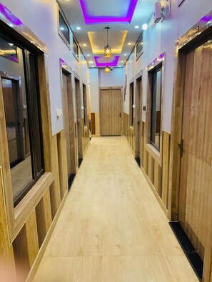 A hallway with wooden doors and a light-colored floor, leading to a room with a door at the end. - Shri Radhe Radhe Paying Guest House (Faizabad)