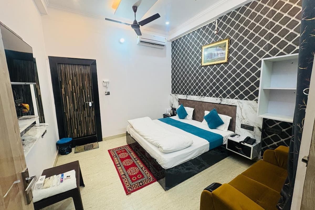 A bedroom with a bed, bedside tables, a nightstand, a ceiling fan, and a patterned wall.