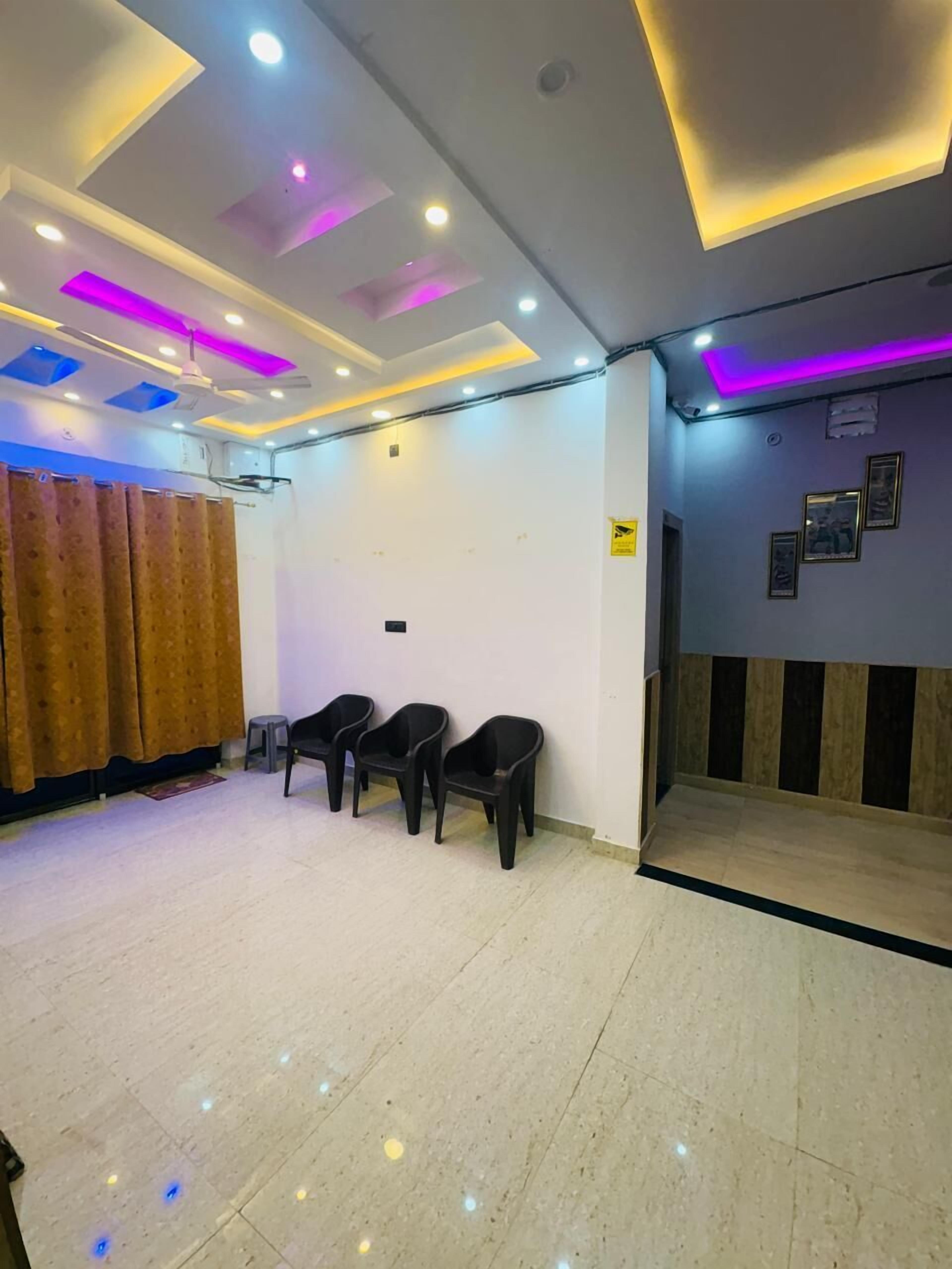A room with a tiled floor, a ceiling with recessed lighting, and a wall with framed pictures.