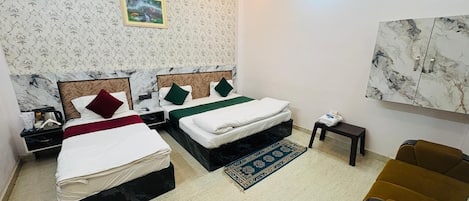 Habitación de hotel con dos camas, ventilador de techo, una mesita, un sofá y una pared con diseño de mármol.