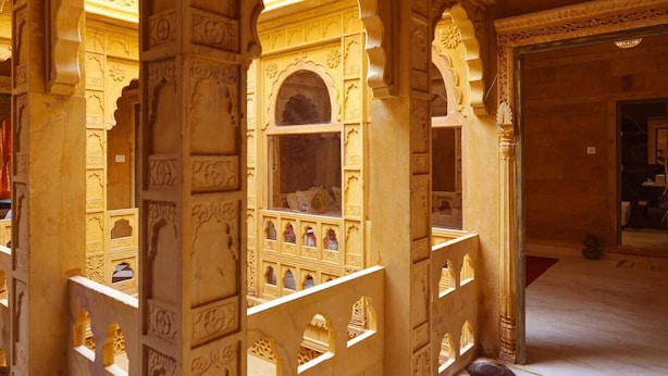 An ornate room with intricate carvings and a balcony with a railing. - Hotel Garh Meera (Jaisalmer)