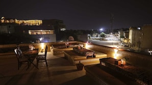 A rooftop terrace with a table and chairs, a sofa, and a decorative railing. - Hotel Garh Meera (Jaisalmer)