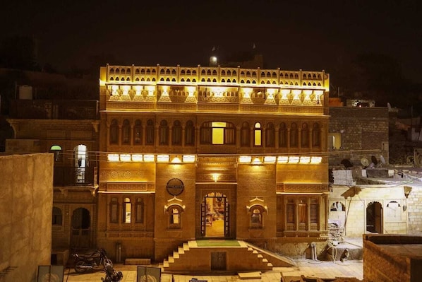 A historic building with a central courtyard, arched windows, and a staircase leading to the entrance.