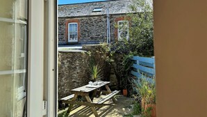 A stone building with a wooden door, a stone wall, and a wooden bench. - Porthilly by Interhome (Mevagissey)