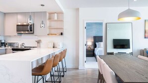 Una cocina moderna con una isla grande, taburetes de bar y un área de comedor con mesa y sillas de madera.
