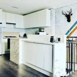 A modern kitchen with white cabinets, a marble countertop, and a pot on the stove. - Perfect Located Apartment in the Heart of Hotham (Hotham Heights)