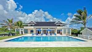 A two-story house with a swimming pool, blue umbrellas, and a well-maintained lawn. - Ocean Mist Villa - by ZenBreak (Belair)