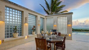 A dining area with a table set for six, surrounded by large windows with decorative glass panels. - Ocean Mist Villa - by ZenBreak (Belair)