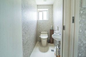 Un baño pequeño con inodoro, lavamanos y una ventana.