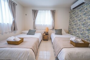 Una habitación de hotel con dos camas, una mesita de noche pequeña con lámpara y una ventana con cortinas.