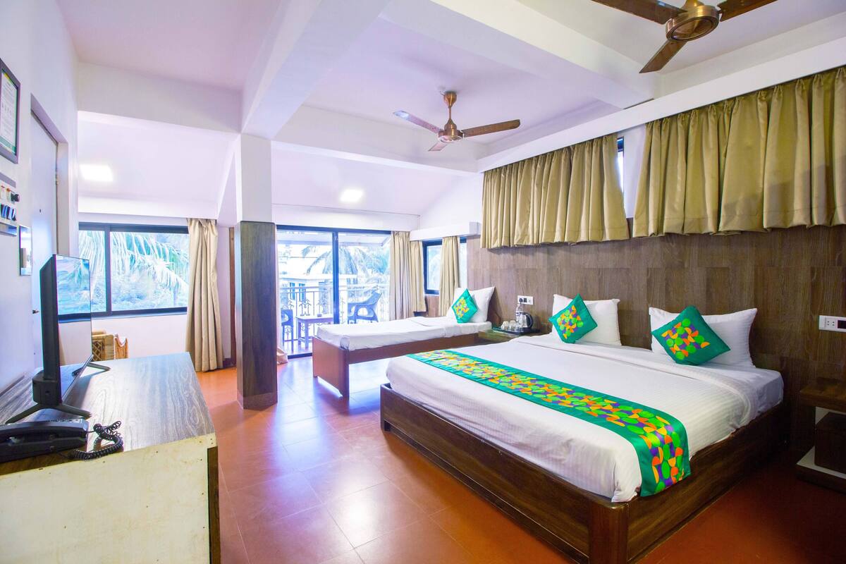 A hotel room with a large bed, a desk, a ceiling fan, and a view of the outdoors.