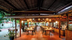 An indoor restaurant with wooden tables and chairs, a tiled floor, and hanging lanterns. - Treebo Kristal Sands Beach Resort with Swimming Pool (Calangute)