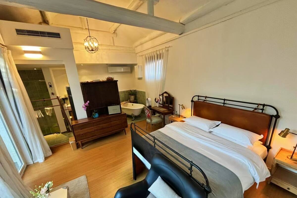 A hotel room with a bed, a desk, a chair, a bathroom, and a TV.