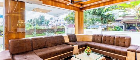 A modern living room with a sectional sofa, a glass coffee table, and a ceiling fan.