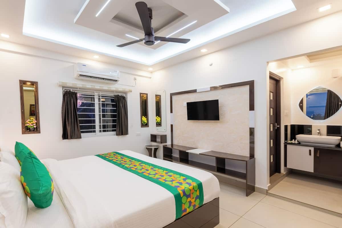 A modern hotel room with a bed, a desk, a TV, and a bathroom.