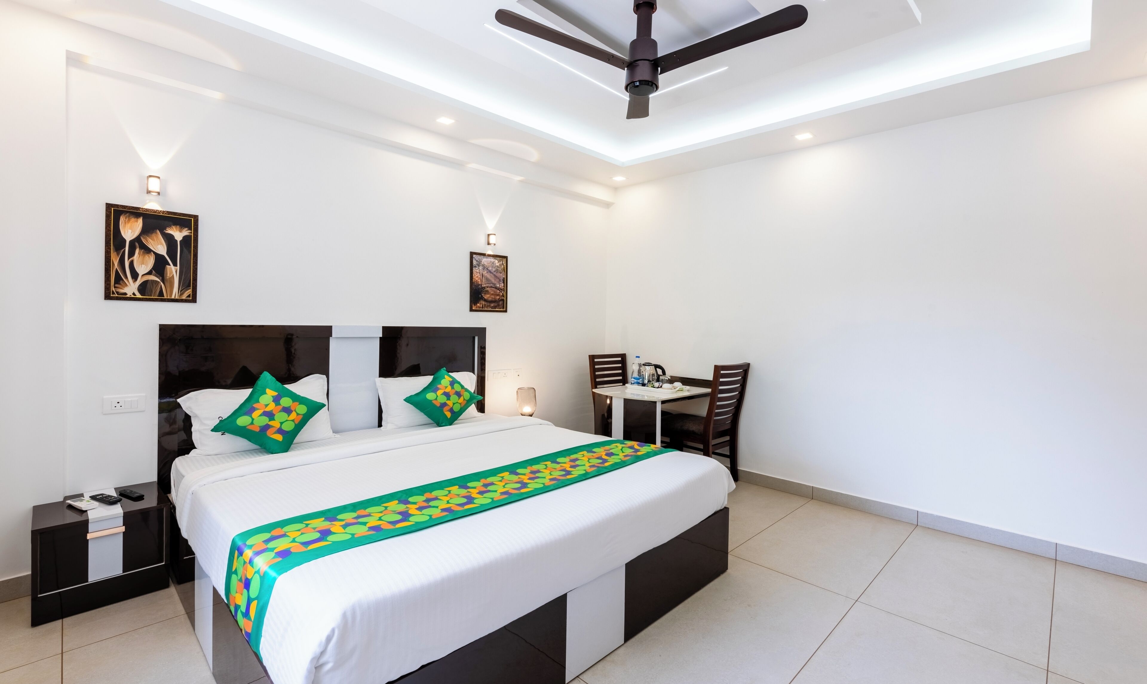 A modern hotel room with a large bed, a desk, and a ceiling fan.