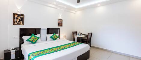 A modern hotel room with a large bed, a desk, and a ceiling fan.