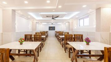 Un comedor amplio con varias mesas y sillas, ventiladores de techo e iluminación empotrada.