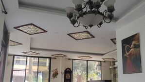 A spacious living area with a chandelier, large windows, a sofa, and a coffee table. - Big House Inn  (Calangute)