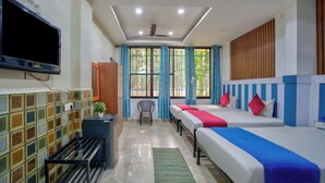A hotel room with two beds, a TV, a ceiling fan, and a window with curtains. - Big House Inn  (Calangute)