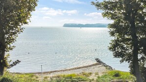 A beach with a wooden walkway leading to the shore, surrounded by trees and vegetation. - "Drifa" - 20m from the sea by Interhome (Hejls)